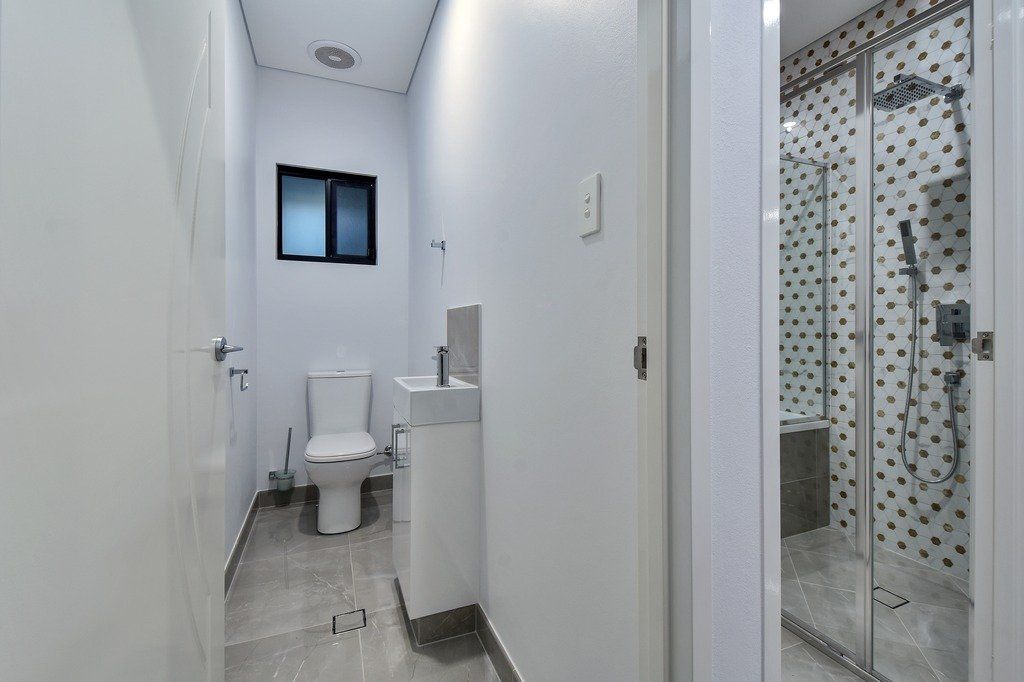 A bathroom with a toilet , sink , and shower.