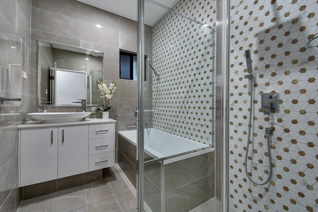 A bathroom with a bathtub , sink , mirror and shower.
