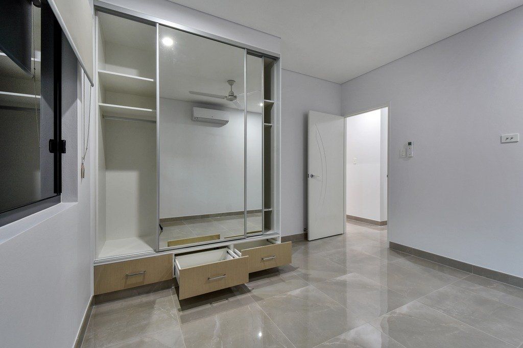 An empty bedroom with a large mirrored wardrobe and a marble floor.
