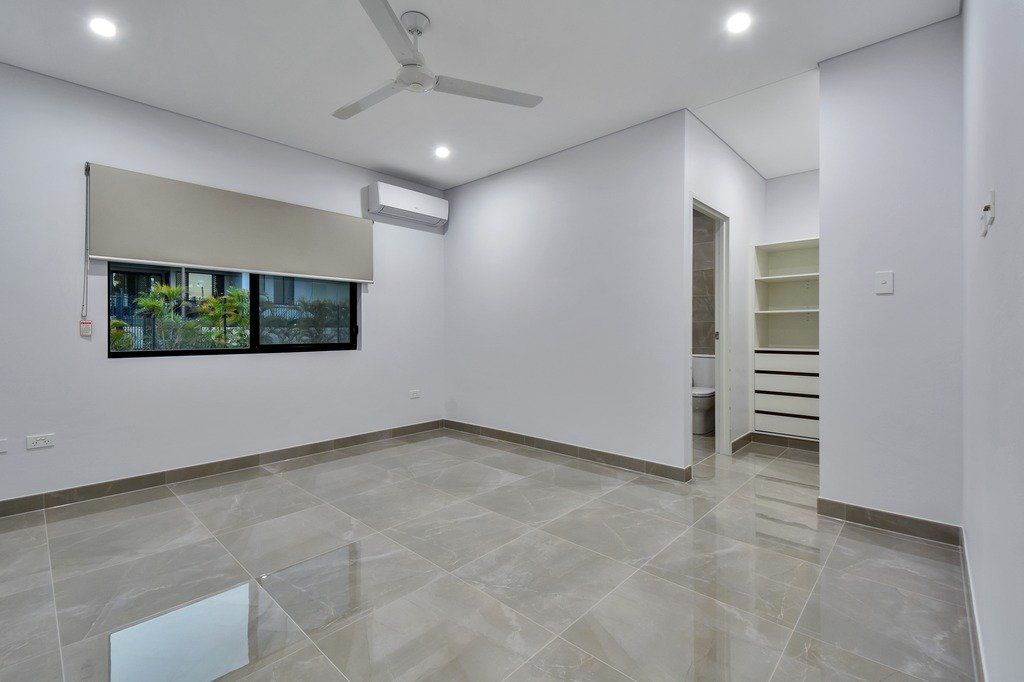 A large empty room with a ceiling fan and a window.