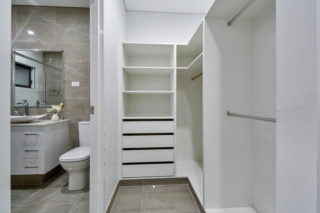 A bathroom with a toilet , sink and walk in closet.