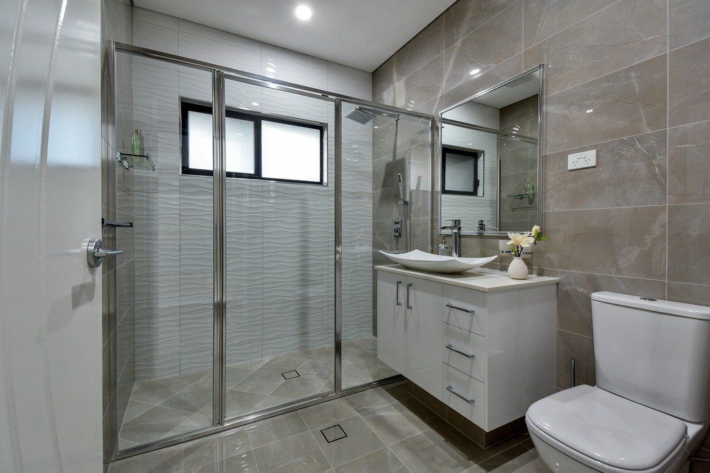 A bathroom with a toilet a sink and a walk in shower