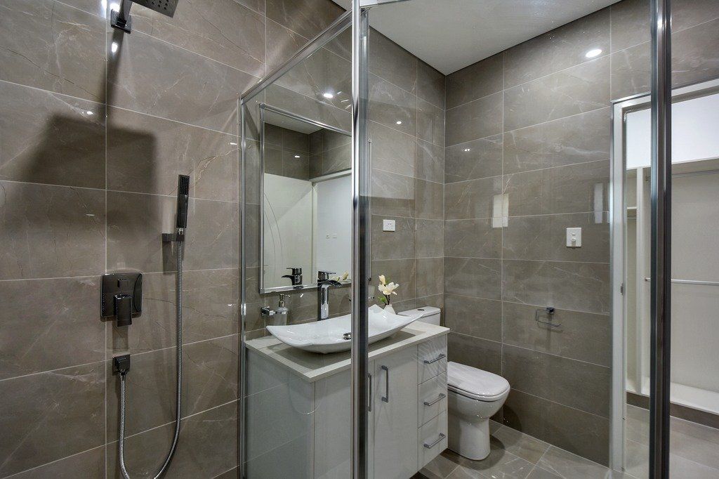 A bathroom with a sink , toilet , shower and mirror.