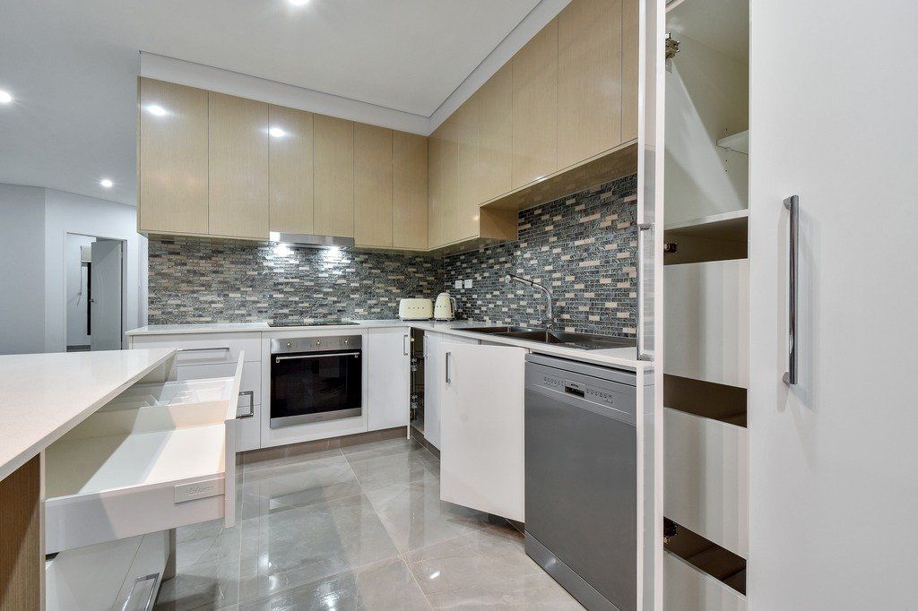 A kitchen with white cabinets and a gray dishwasher