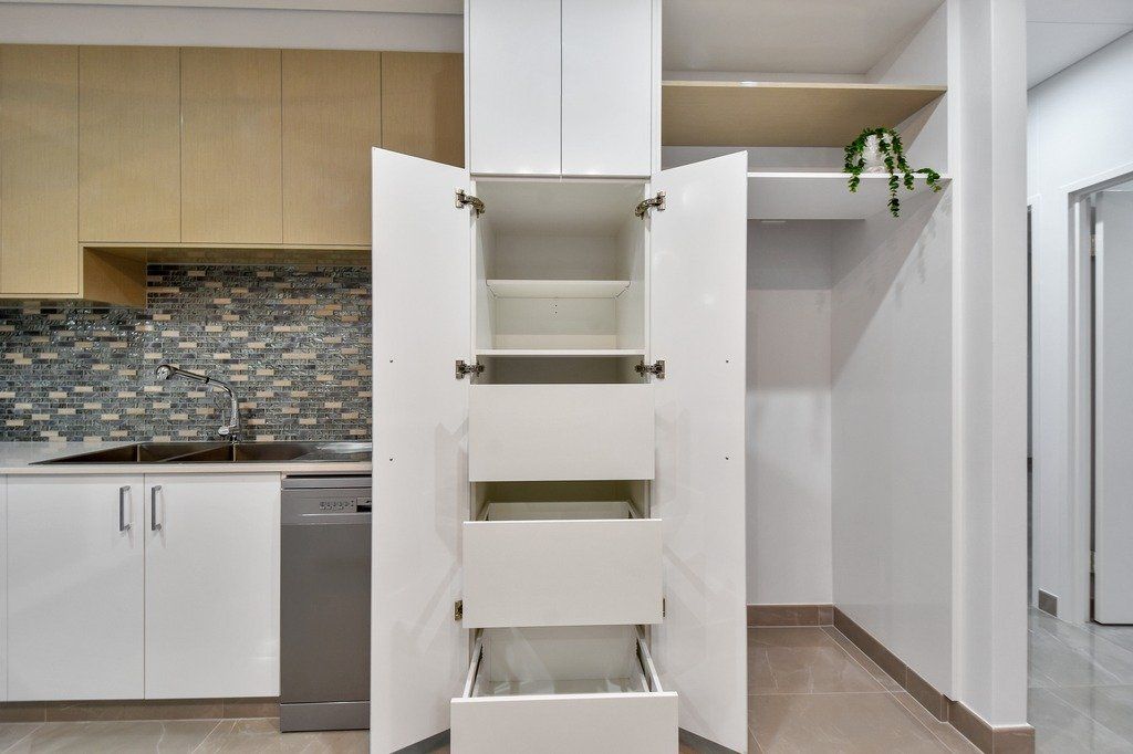A kitchen with white cabinets and drawers and a dishwasher.