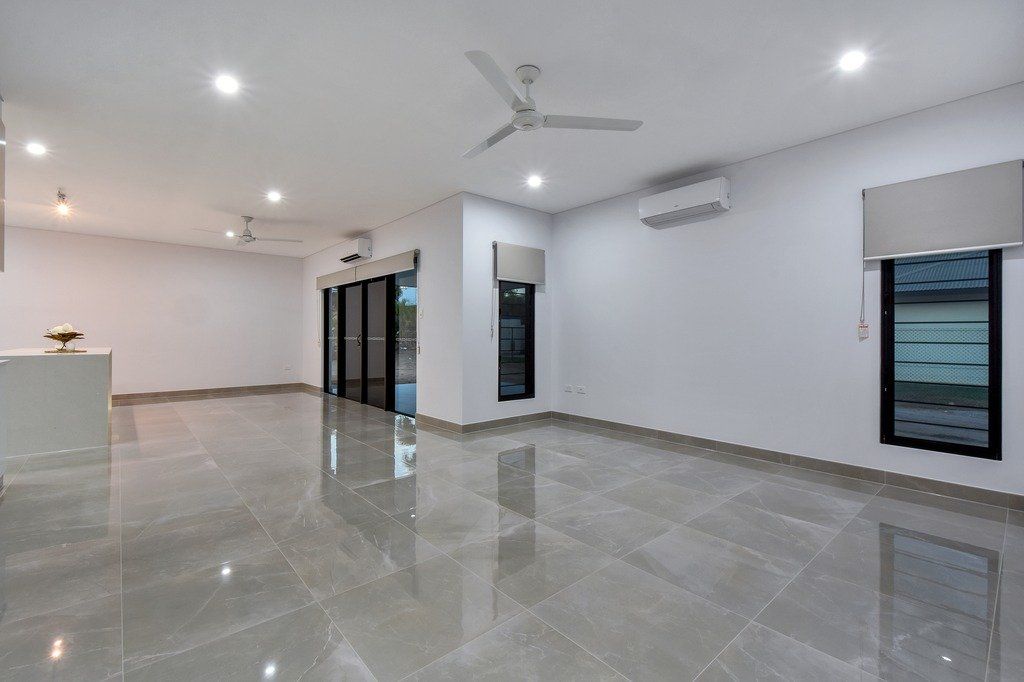 A large empty room with a ceiling fan and a marble floor.