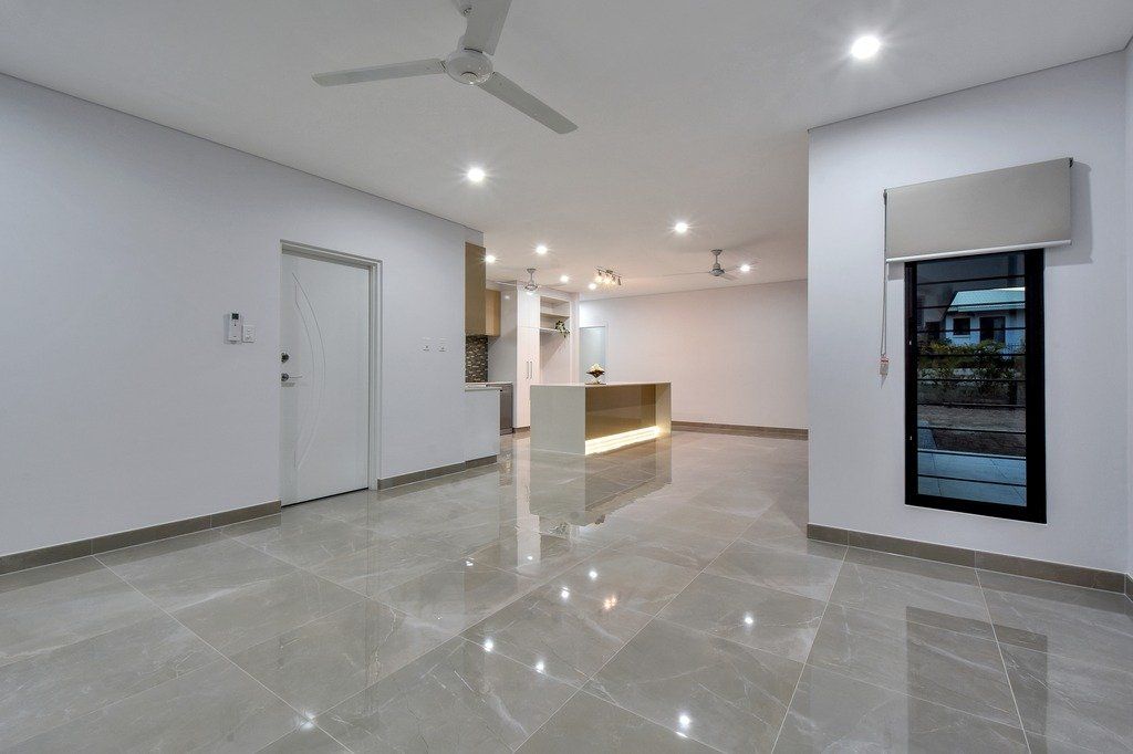 An empty living room with a ceiling fan and a marble floor.