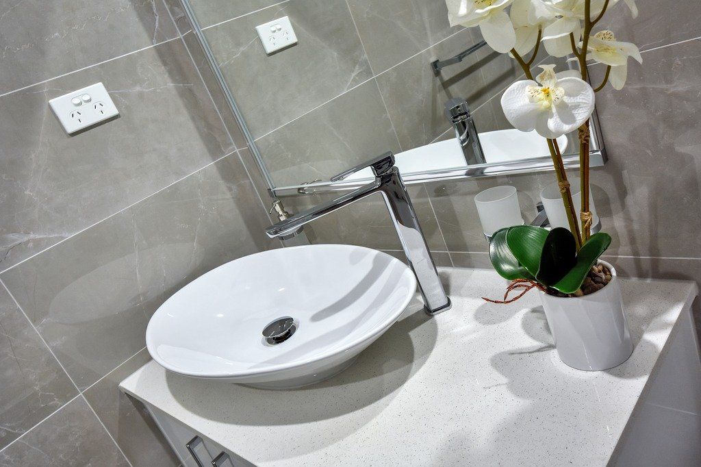 A bathroom with a sink and a vase of flowers on the counter.