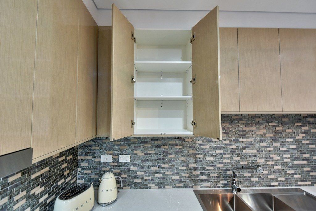 An open cabinet in a kitchen with a stainless steel sink