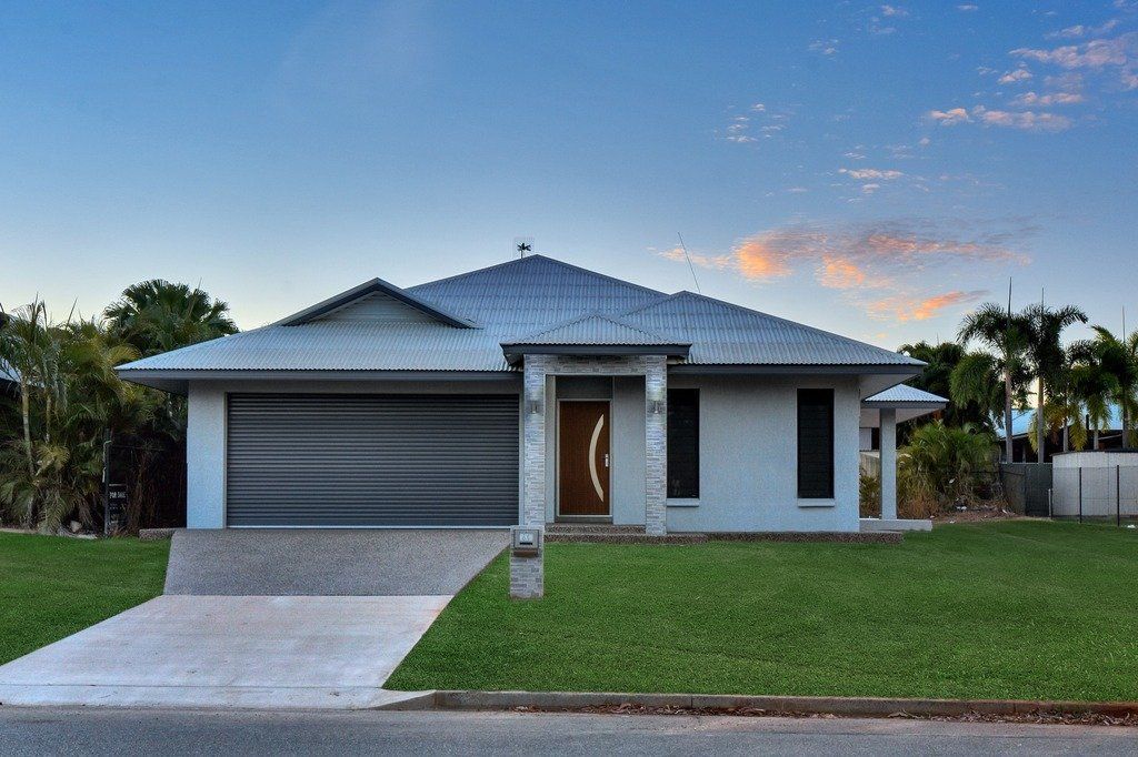 A white house with a gray garage door is sitting on top of a lush green lawn.