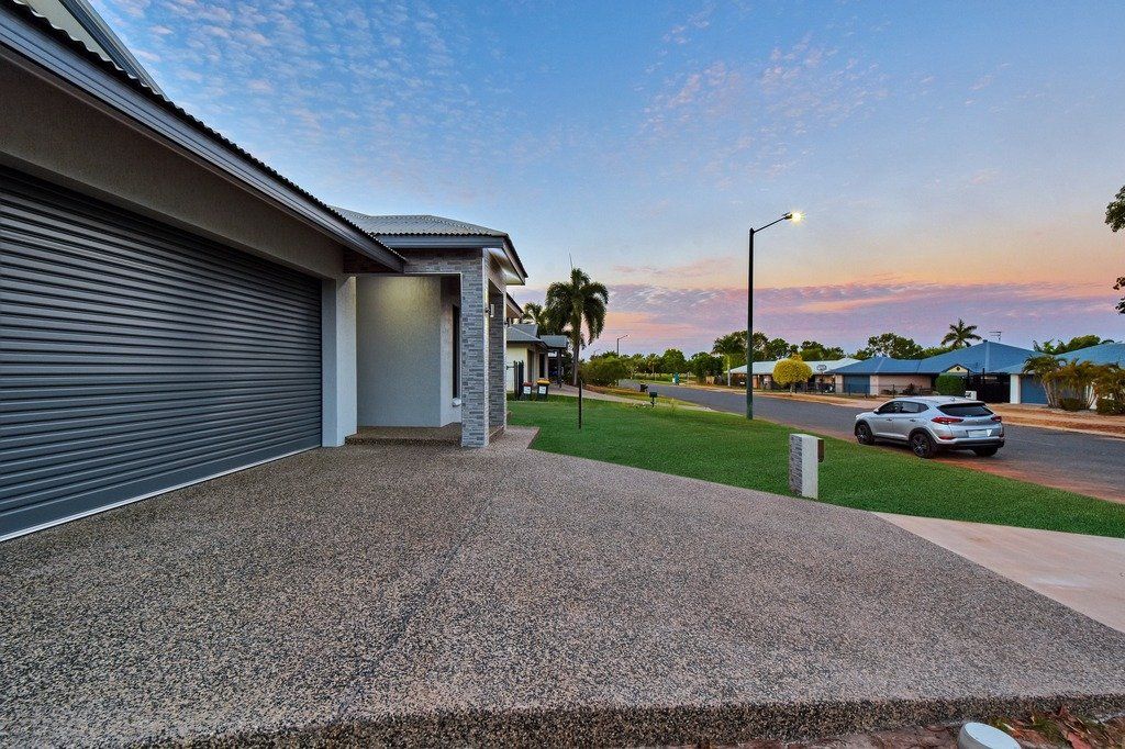 A car is parked in front of a garage next to a house.
