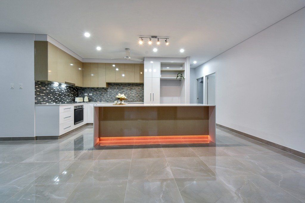An empty kitchen with a large island in the middle of the room.