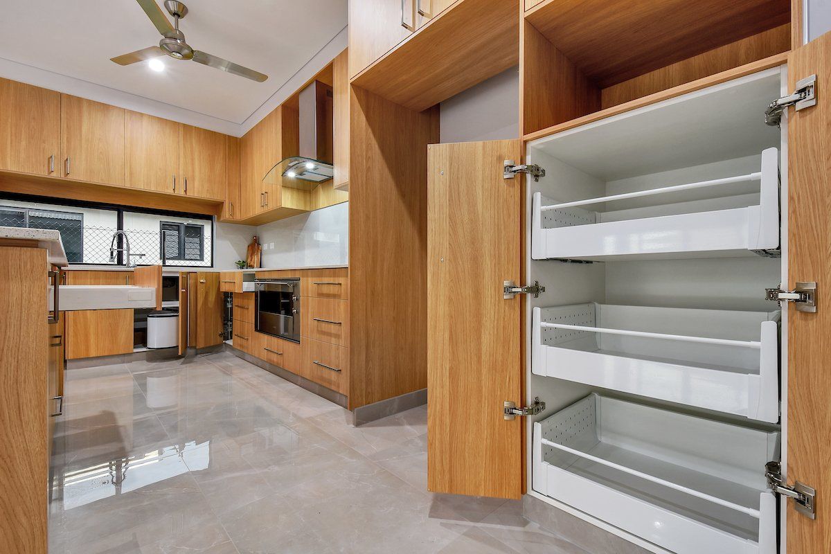 A kitchen with wooden cabinets and white drawers and a ceiling fan.