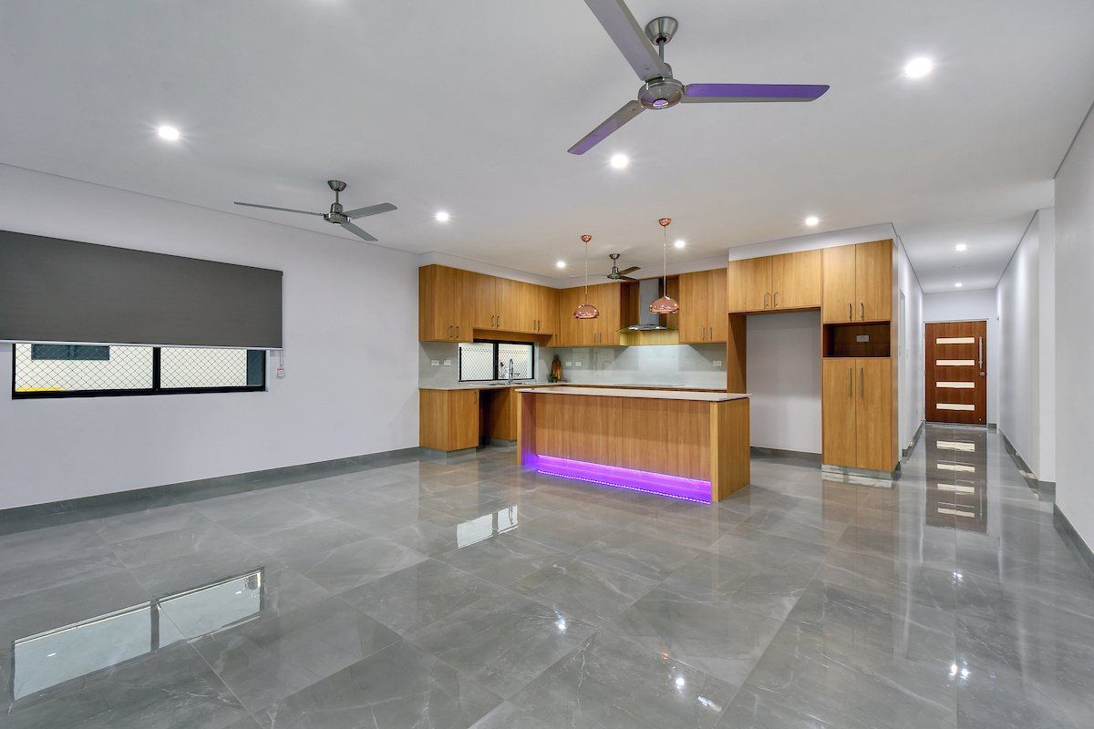 An empty kitchen with a ceiling fan and purple lights