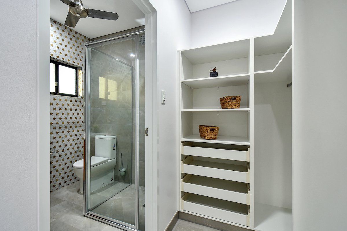 A bathroom with a toilet and a walk in closet.