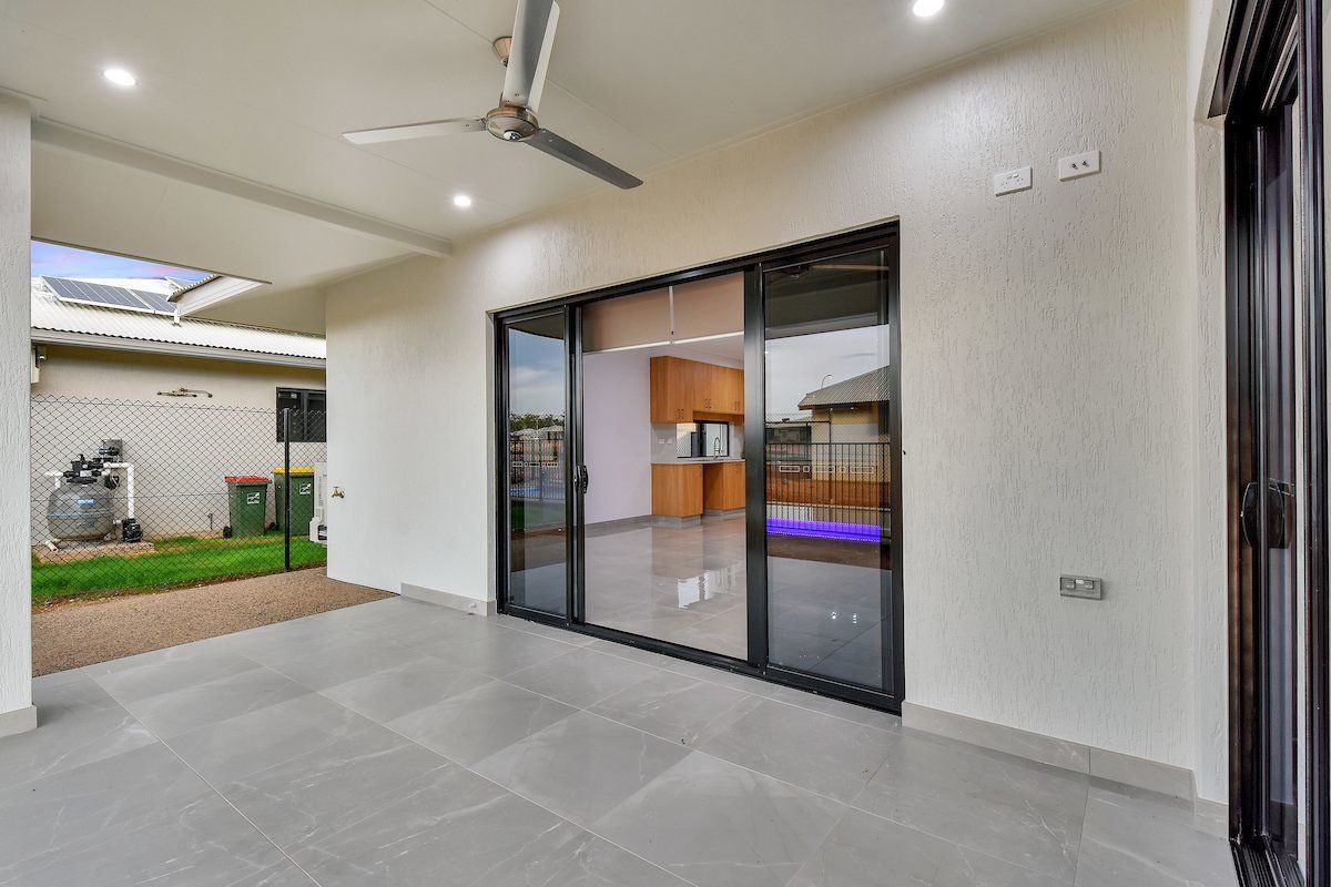 An empty room with a ceiling fan and sliding glass doors.