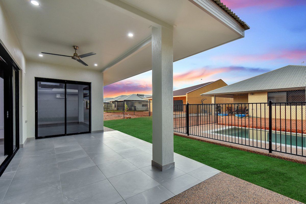 A patio with a ceiling fan and a pool in the backyard of a house.