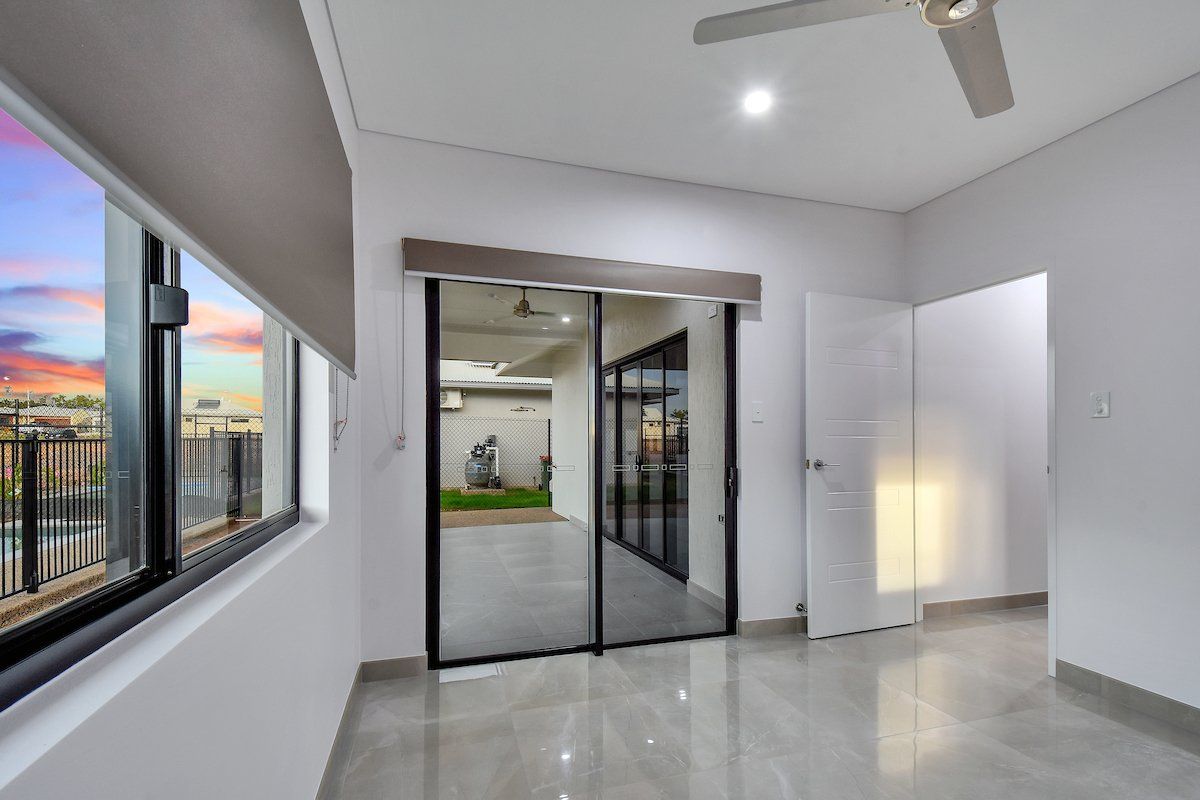 An empty room with sliding glass doors and a ceiling fan.