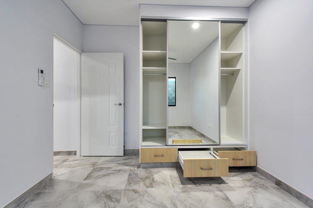 An empty room with a sliding door wardrobe and drawers.