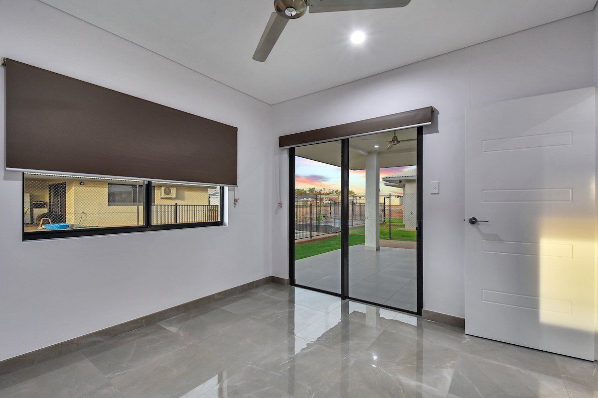 An empty room with sliding glass doors and a ceiling fan.