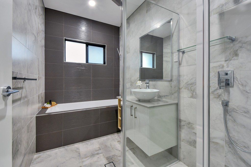 A bathroom with a tub , sink , mirror and shower.