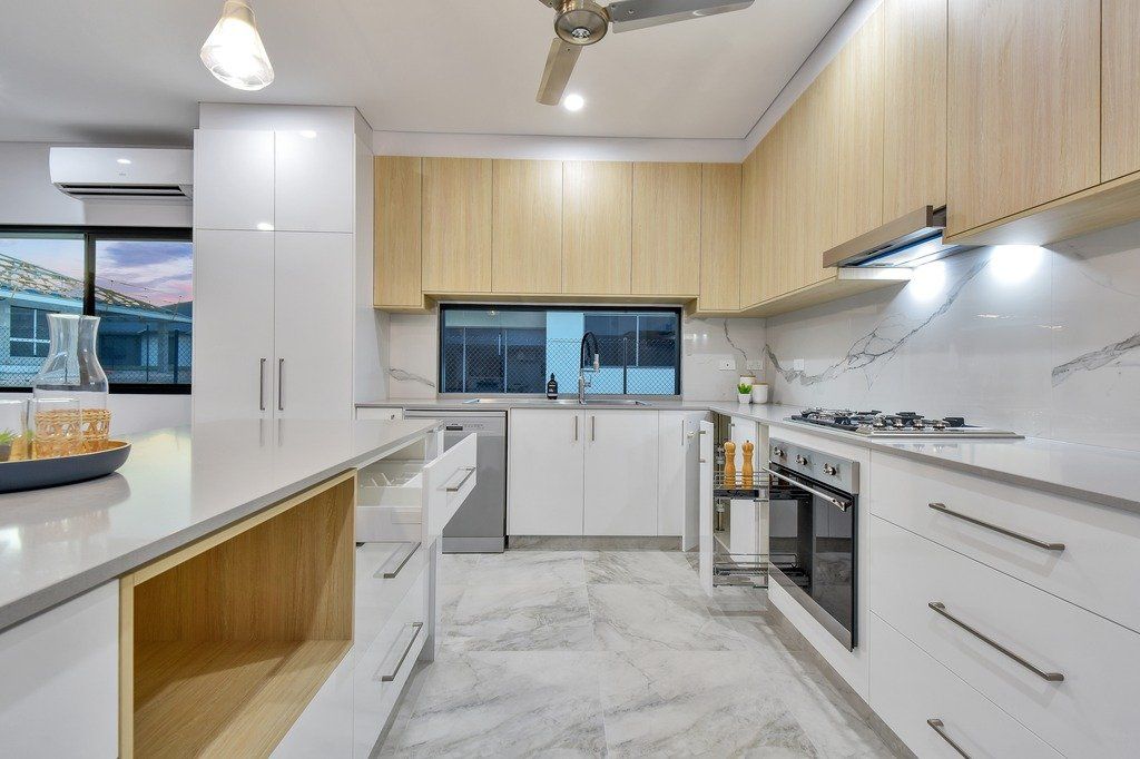 A kitchen with white cabinets and wooden cabinets and a ceiling fan.
