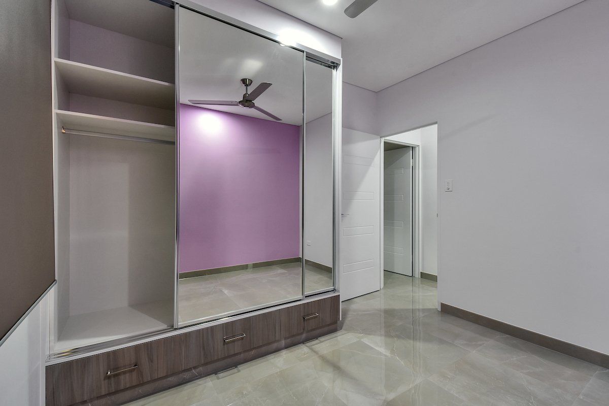 A bedroom with a large mirrored wardrobe and a ceiling fan.