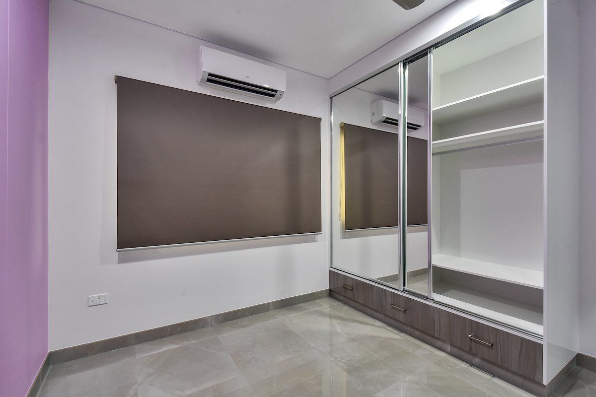 A bedroom with a sliding glass door wardrobe and a purple wall.