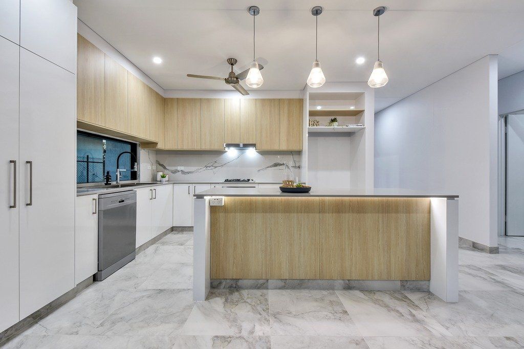 A kitchen with white cabinets and a large island in the middle.