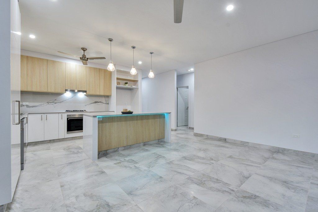 An empty kitchen with white cabinets and a ceiling fan.