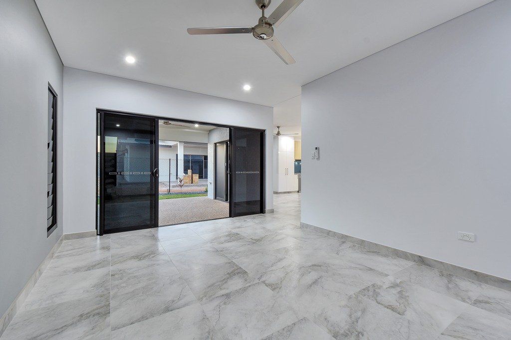 An empty living room with a ceiling fan and a sliding glass door.