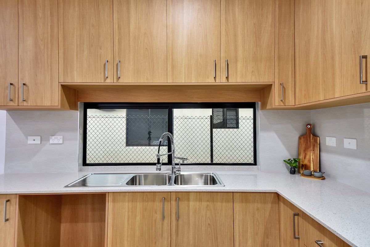 A kitchen with wooden cabinets , a sink , and a window.