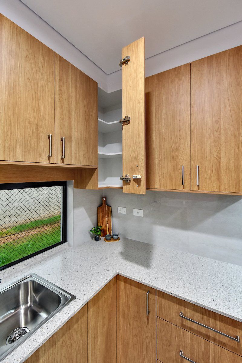 A kitchen with wooden cabinets , a sink , and a window.