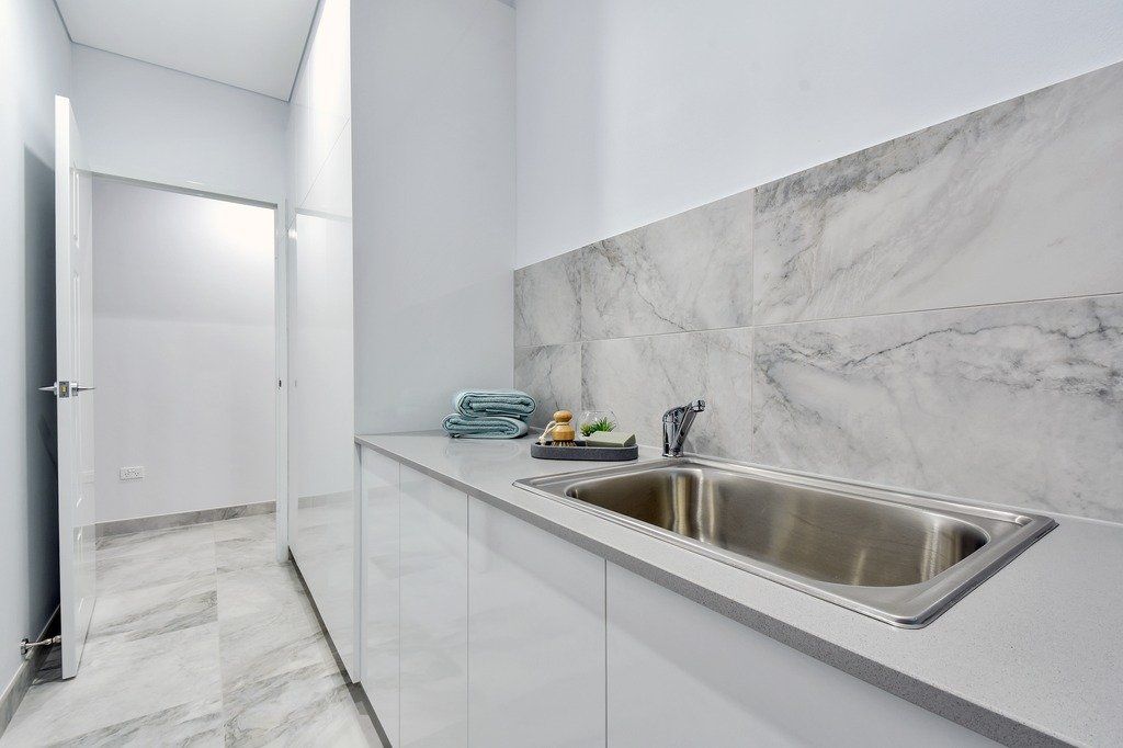 A kitchen with a stainless steel sink and white cabinets.
