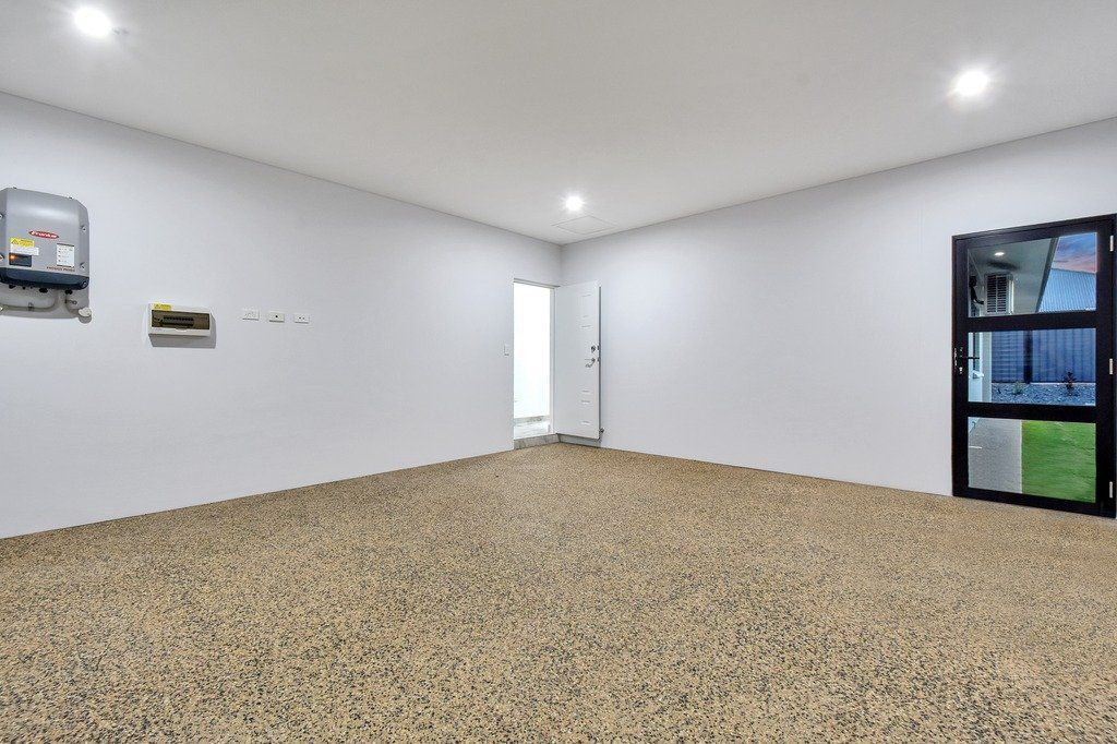 An empty garage with a gravel floor and white walls.