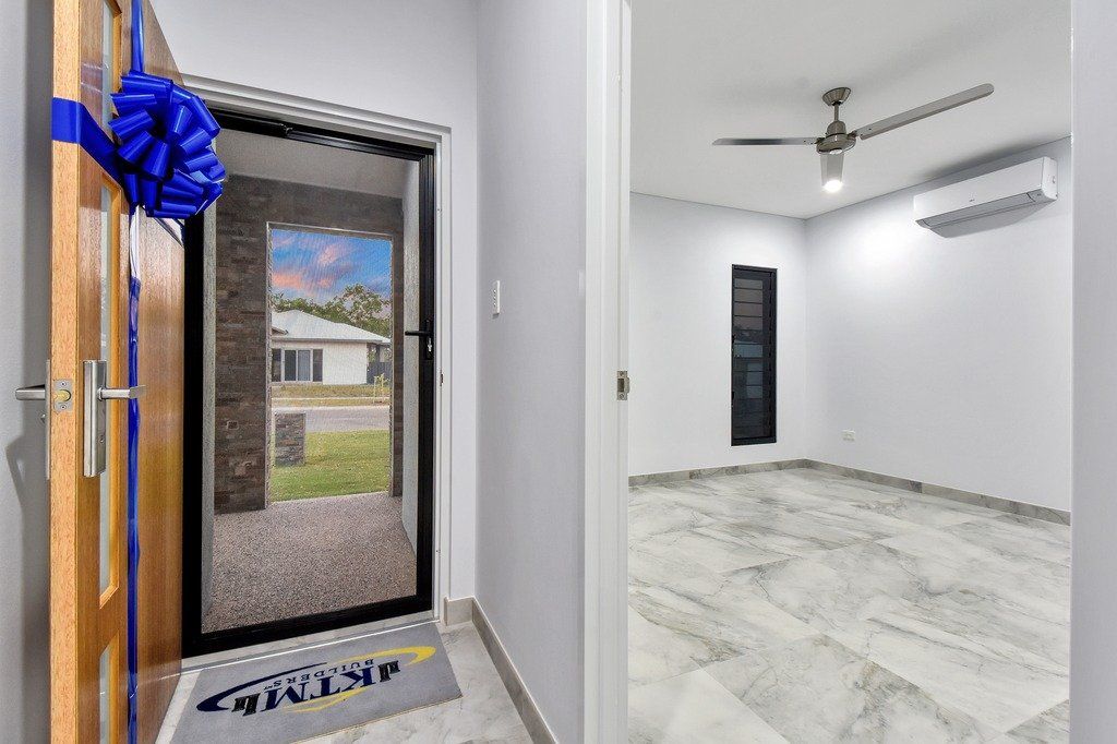 A door with a blue bow on it is open to a room with a ceiling fan.
