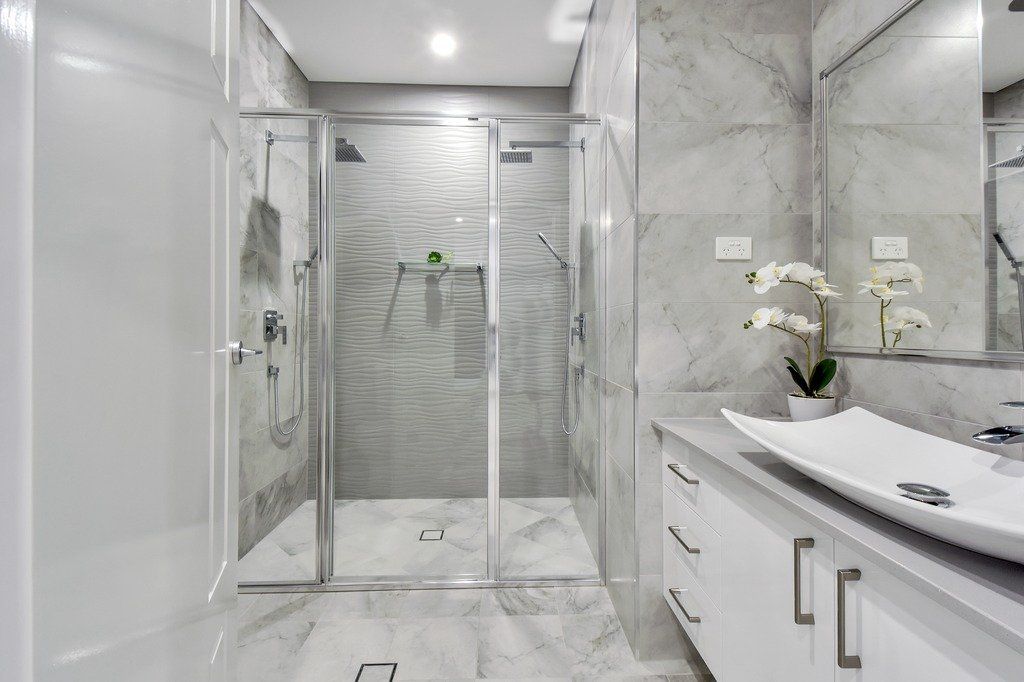 A bathroom with a walk in shower , sink and mirror.