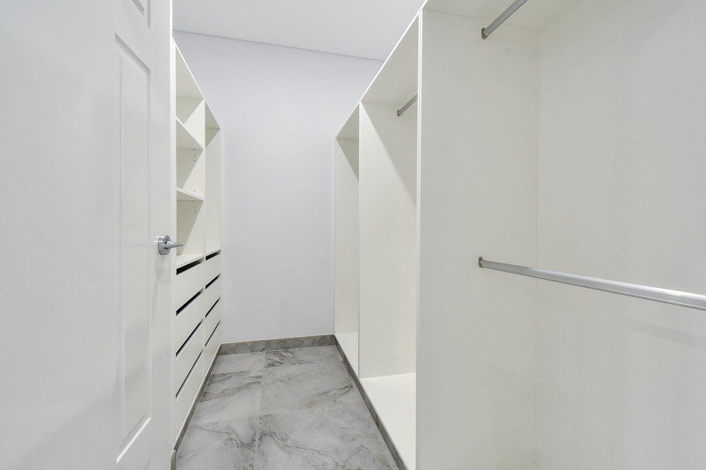 A walk in closet with lots of shelves and clothes racks.