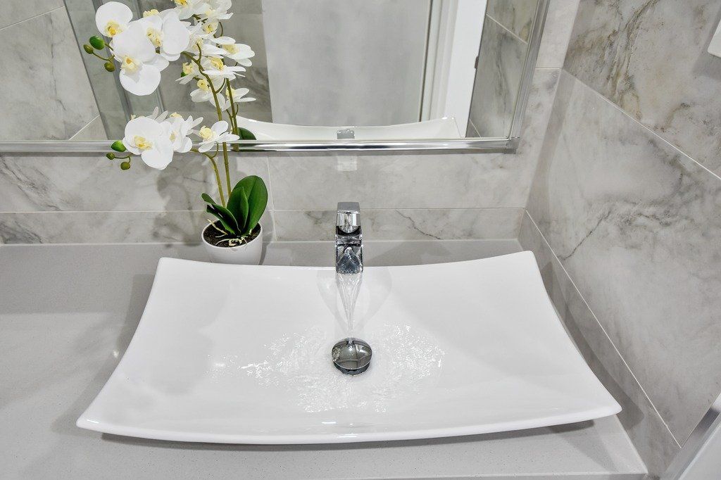 A bathroom sink with water running out of it and a potted plant.