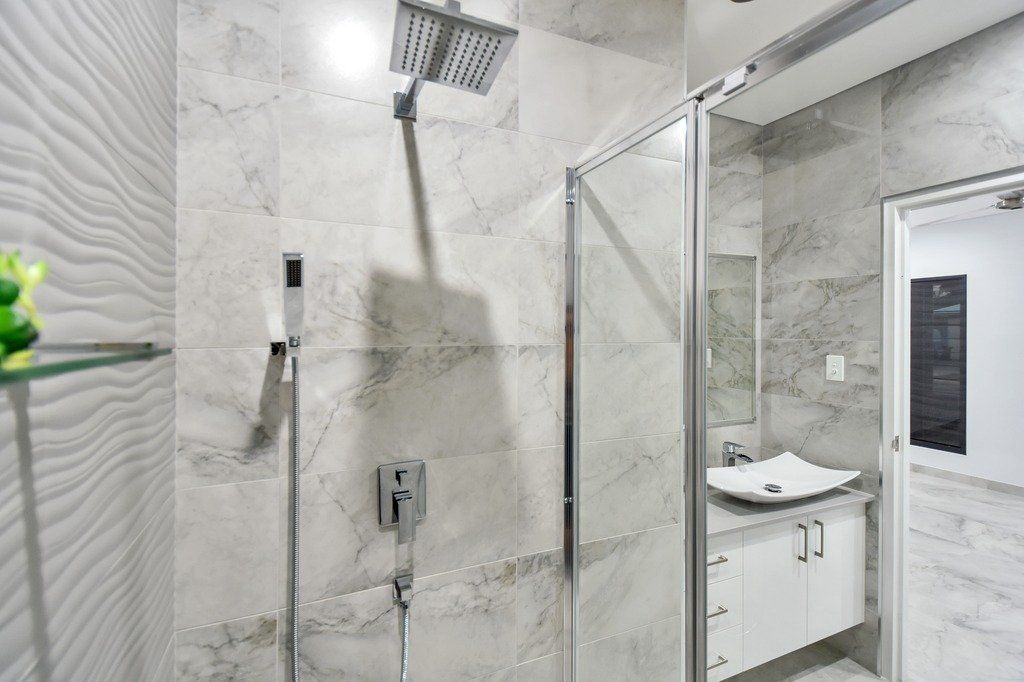 A bathroom with a walk in shower , sink and mirror.