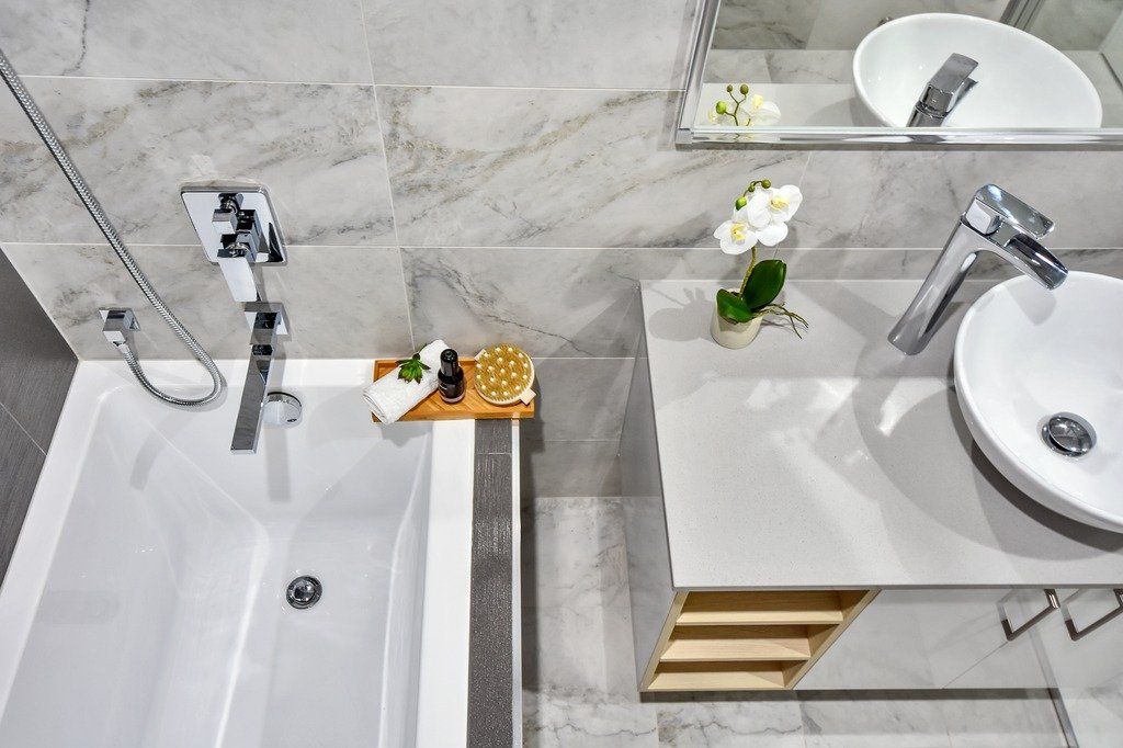 A bathroom with a bathtub , sink and mirror.