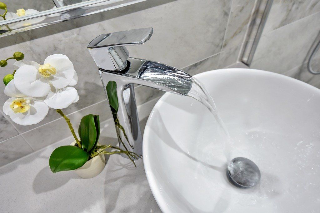 A bathroom sink with a faucet and a flower on the counter.