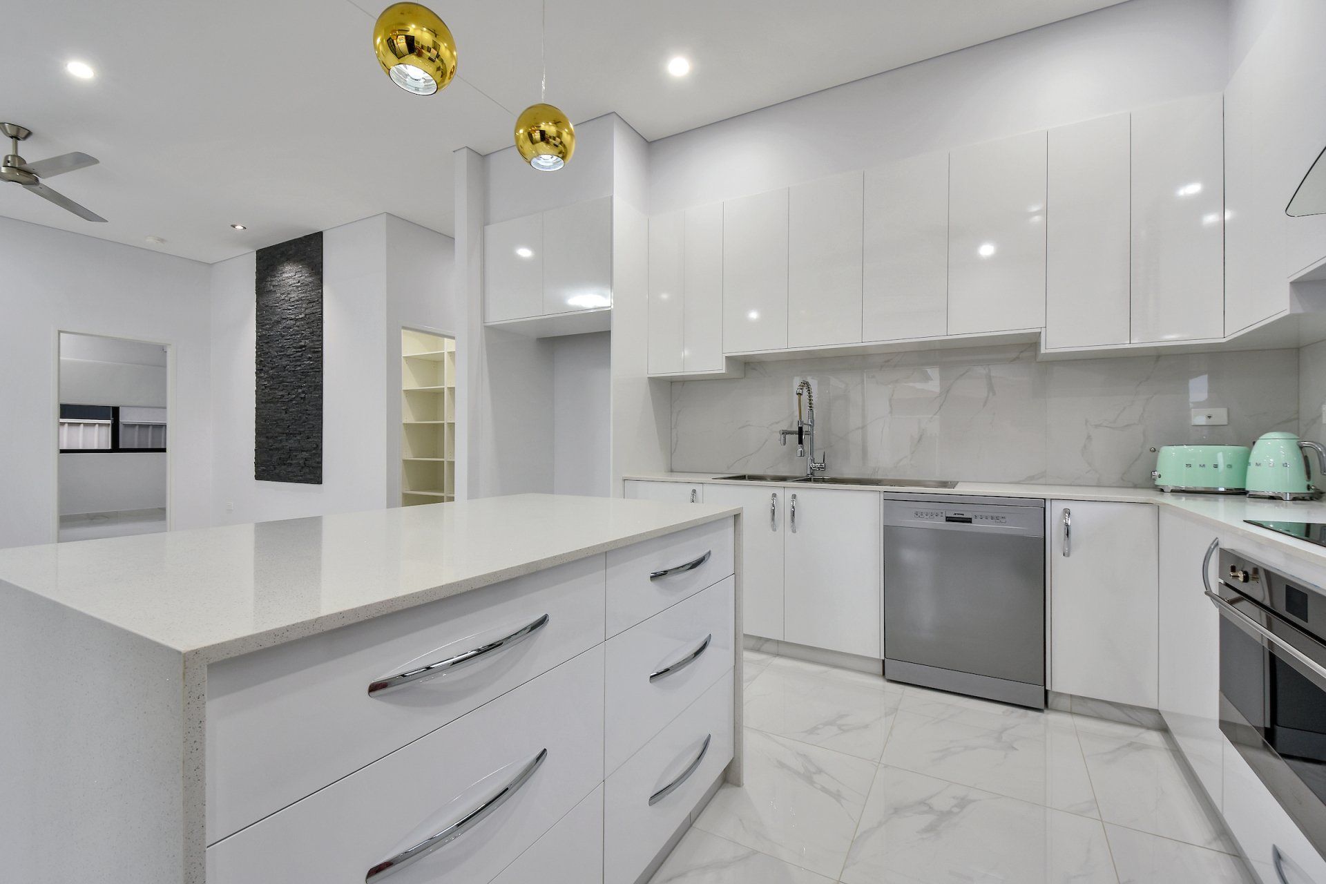 A kitchen with white cabinets , stainless steel appliances , and a large island.