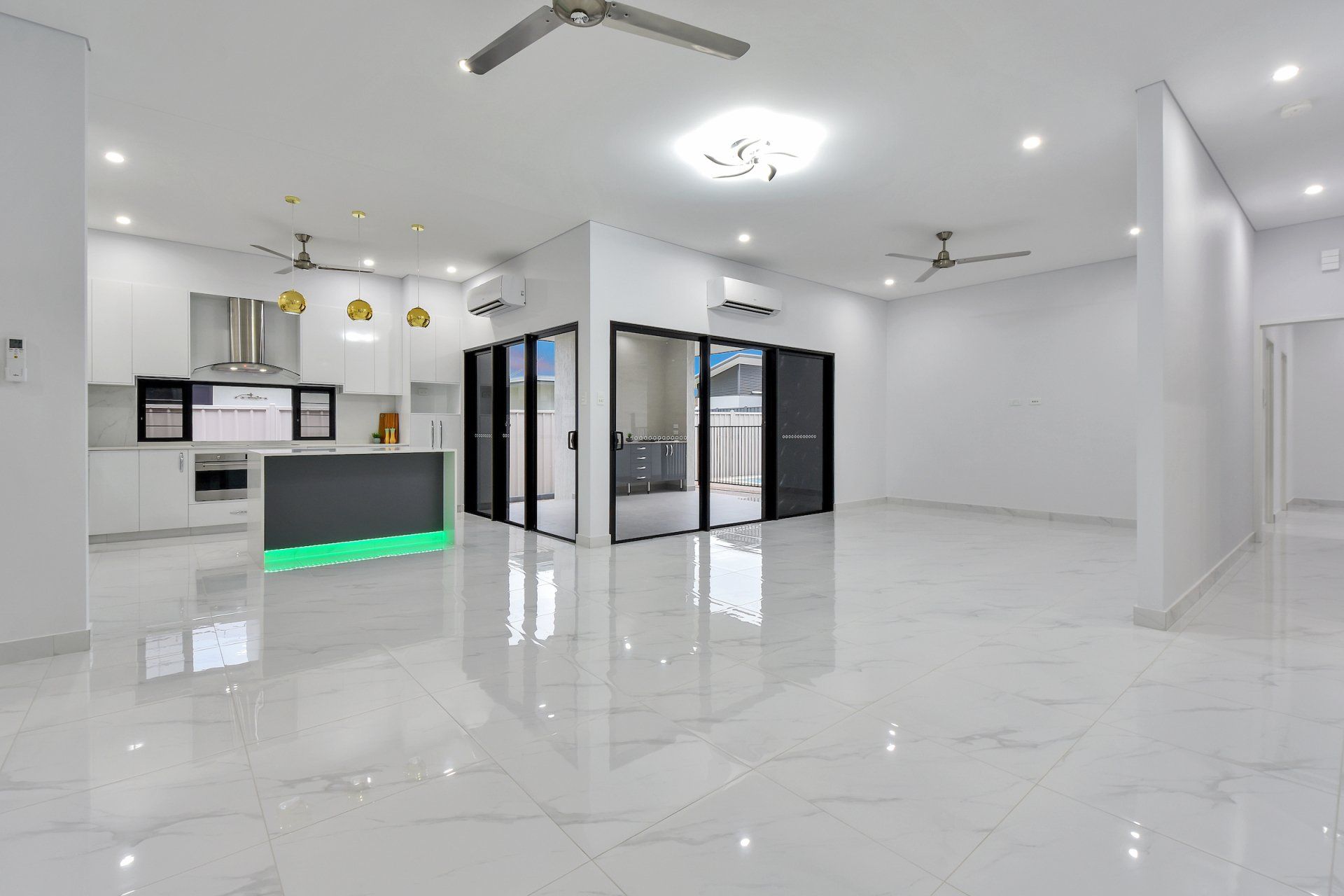 A large empty room with a marble floor and a kitchen.