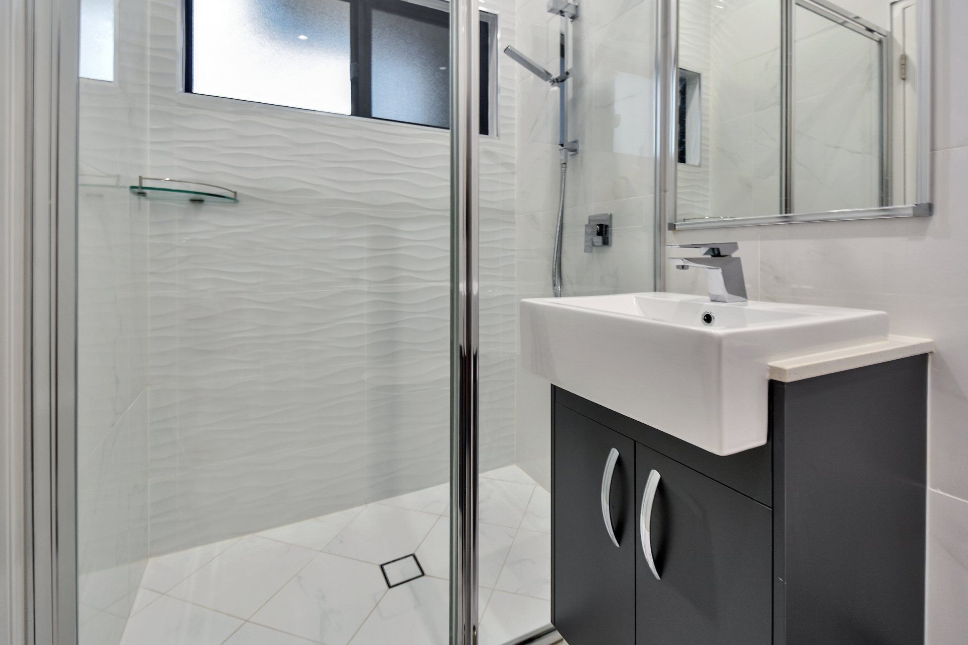 A bathroom with a sink , mirror and shower stall.