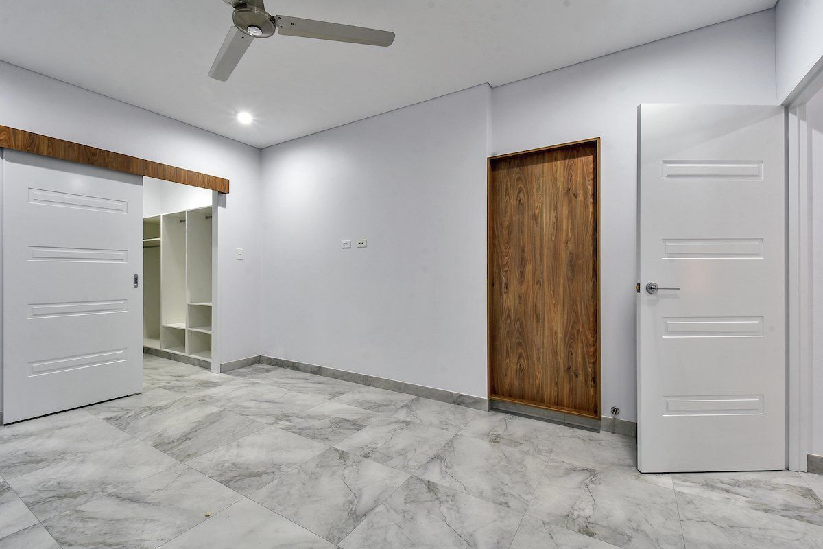 An empty bedroom with a ceiling fan and sliding doors.
