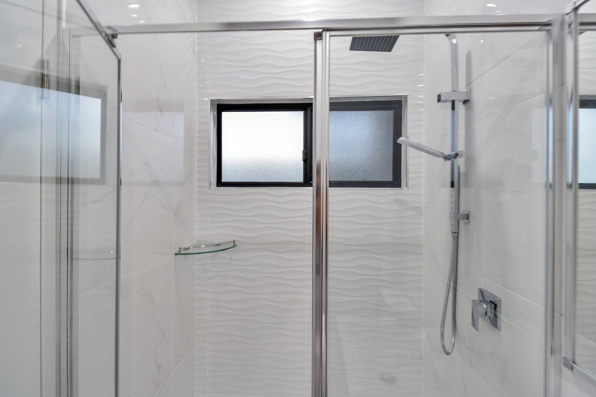 A bathroom with a sliding glass shower door and a window.