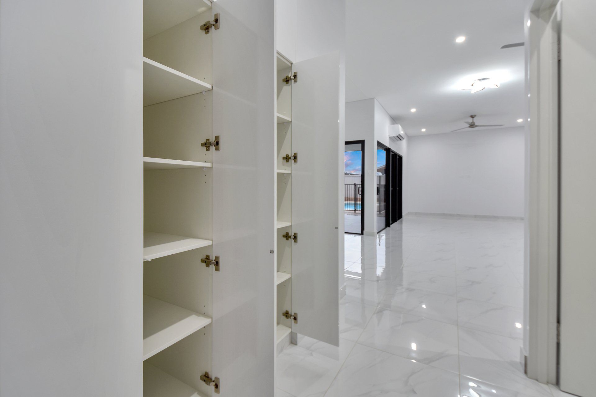 A hallway with white cabinets and shelves in a house.