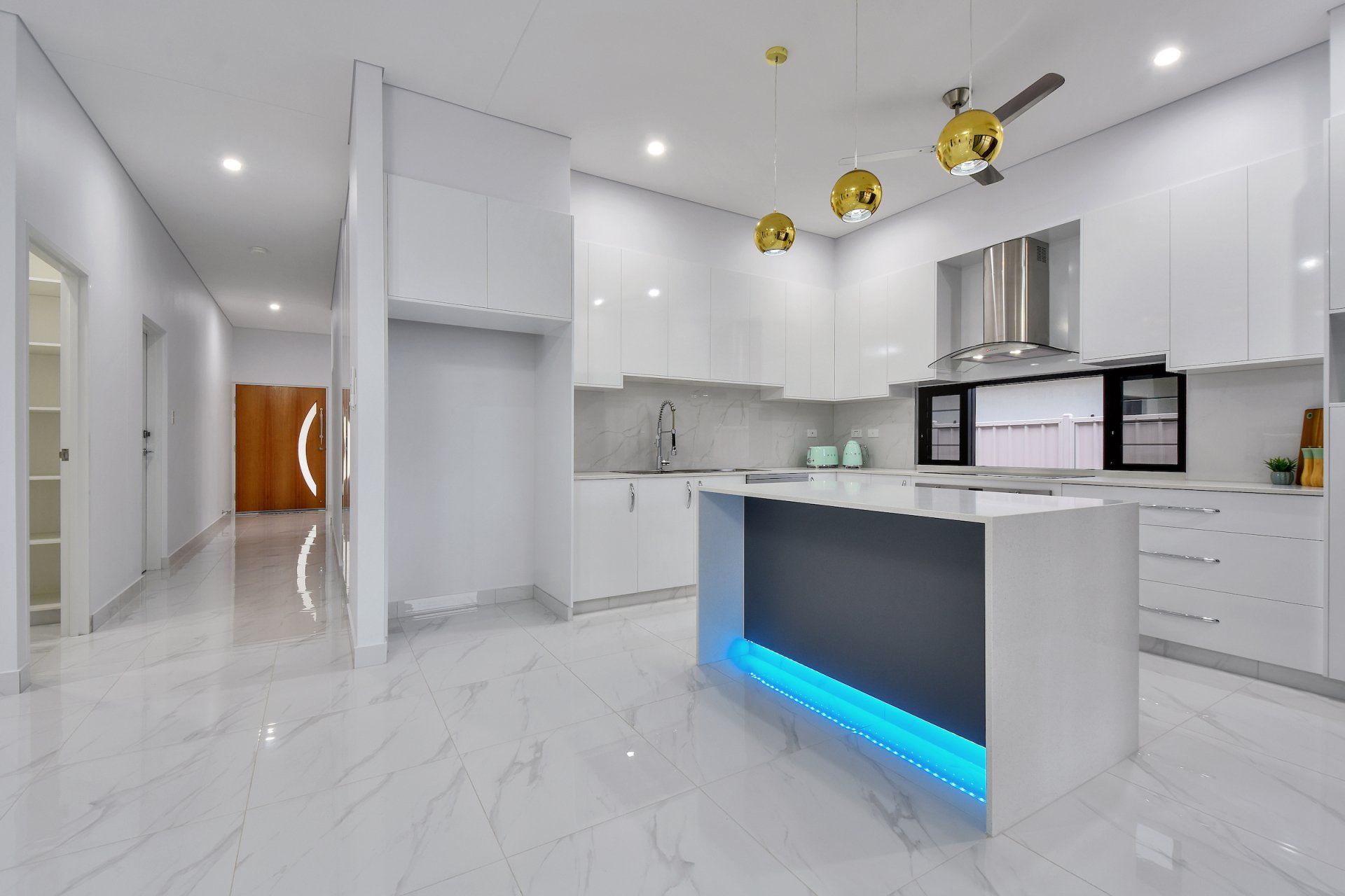 A kitchen with white cabinets and a blue light on the island