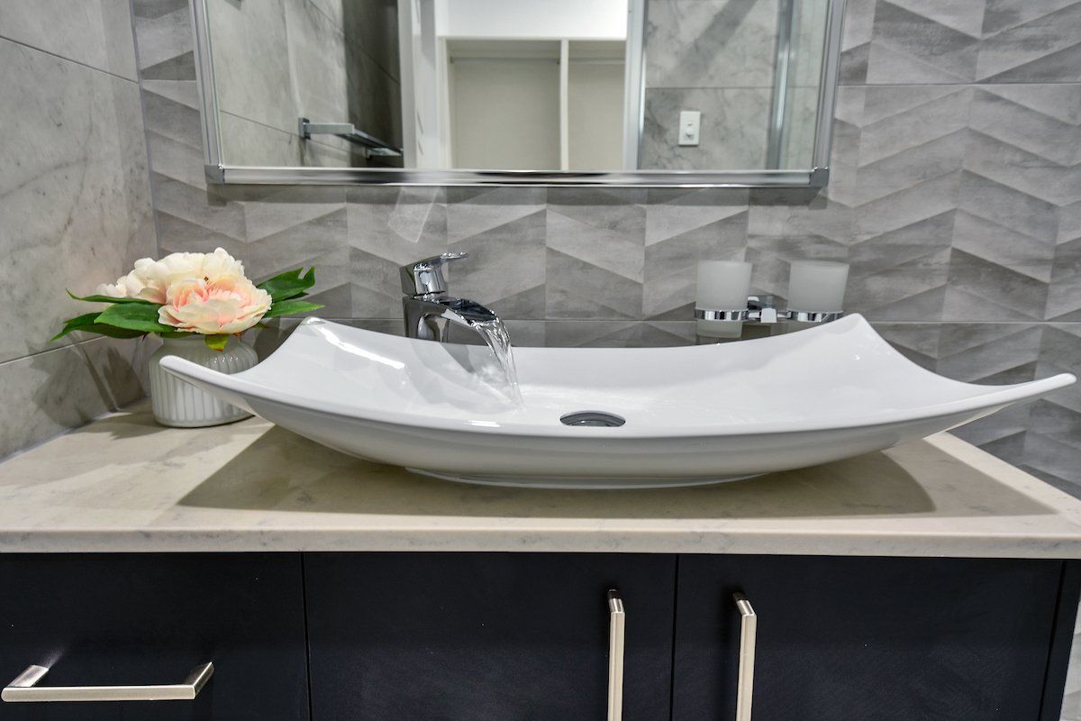 A bathroom sink with a vase of flowers on top of it.